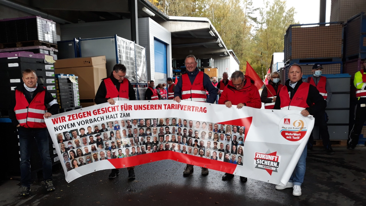 Kollegen halten Banner mit Gesichtern beim Warnstreik