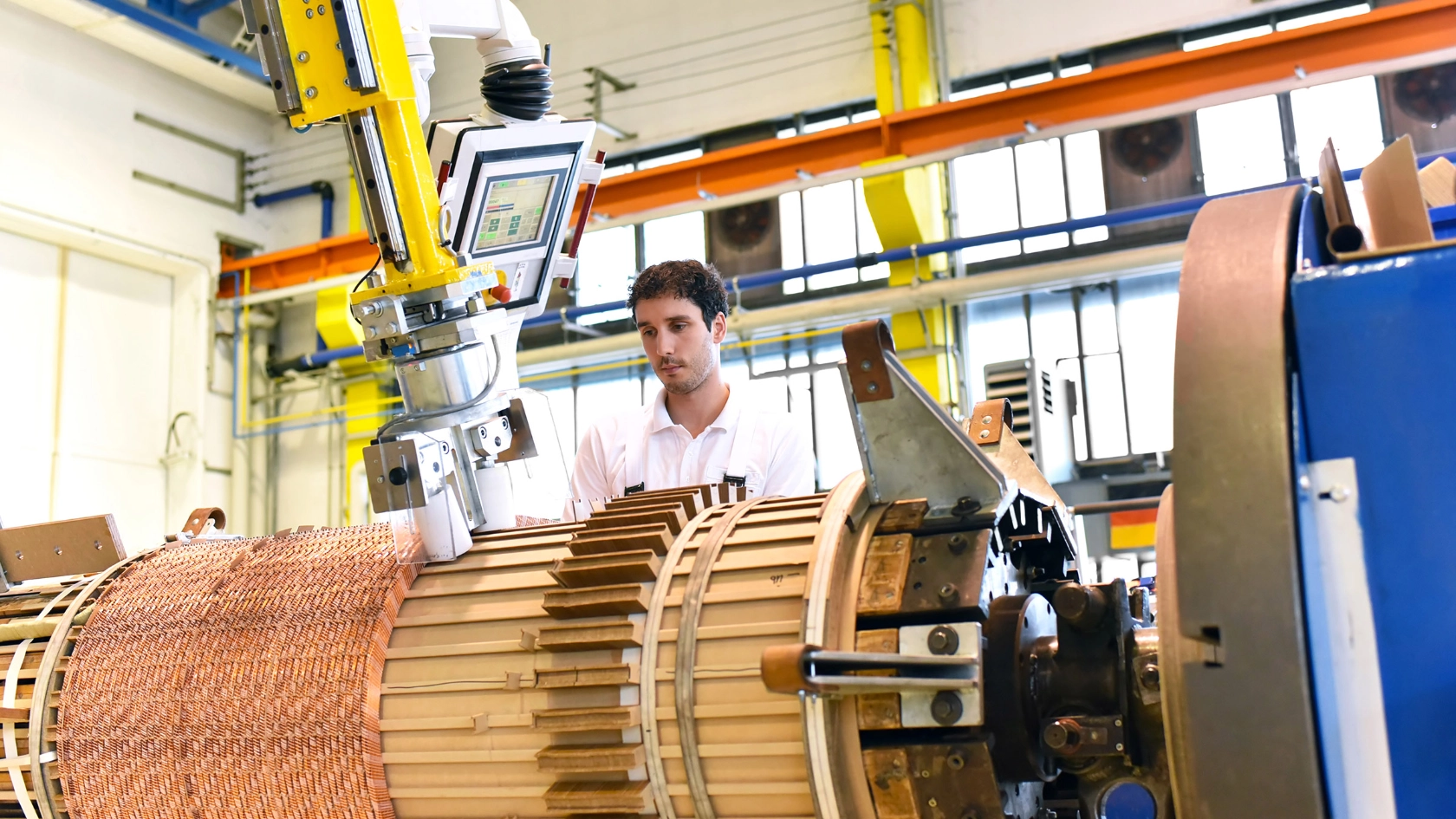 Ein junger Mann arbeitet an einer Maschine in einer Fabrik zur Herstellung von Transformatoren.