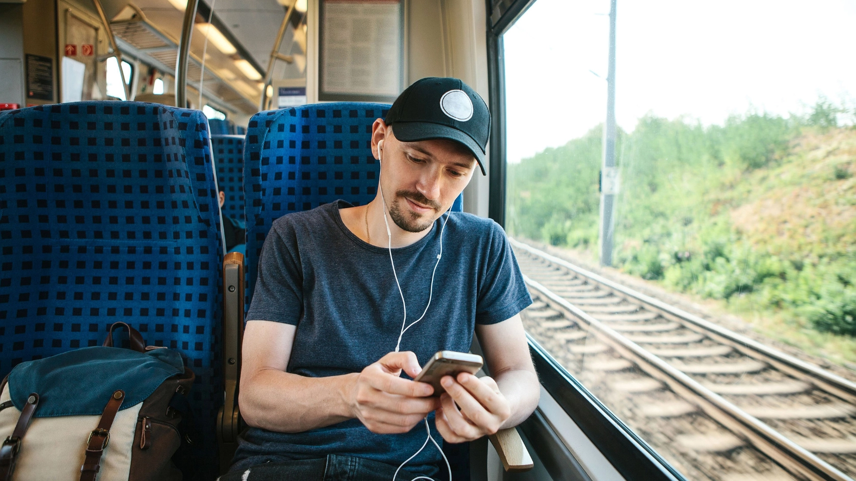 Junger Mann mit Smartphone in der Bahn