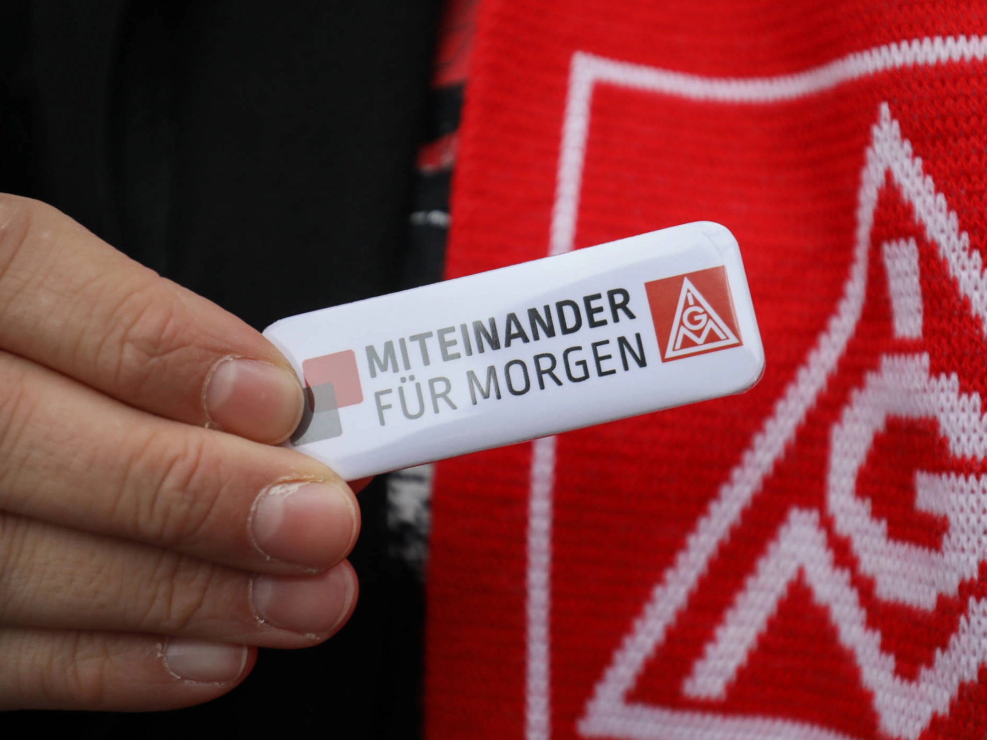 Jemand hält einen Anstecker mit der Aufschrift "miteinander für morgen".