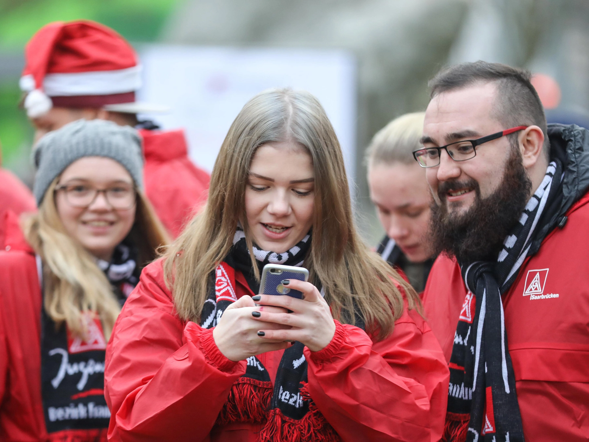 Junge Frau tippt in ihr Handy. Ein Junger Mann schaut mit auf das Gerät.