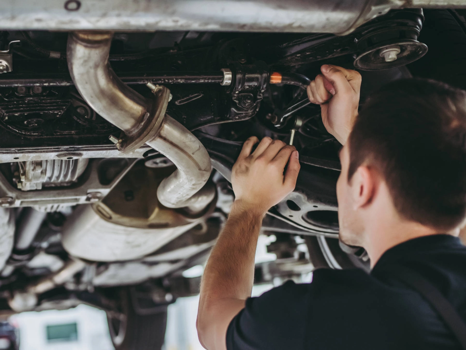 Zwei Männer stehen unter einer Hebebühne und arbeiten an einem Auto.