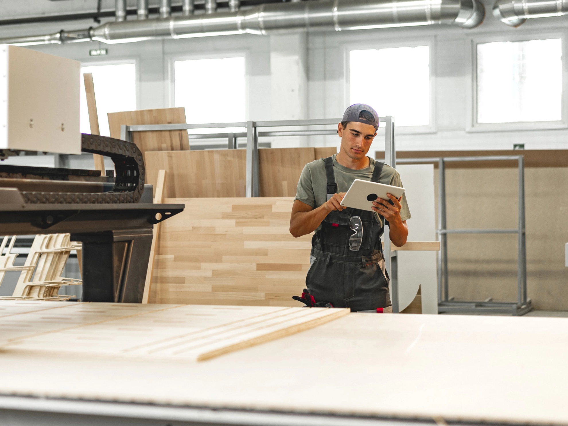 Beschäftigter bedient in einer Möbelfabrik eine Maschine zur Holzverarbeitung