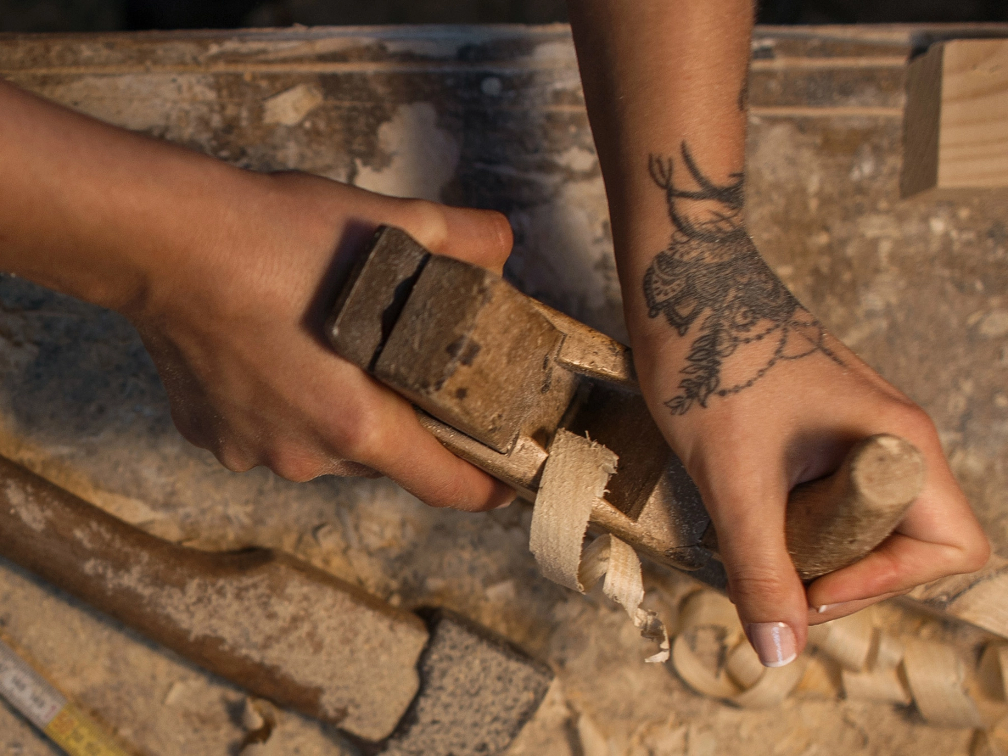 Weibliche Hände mit einer Tätowierung bei der Holzbearbeitung